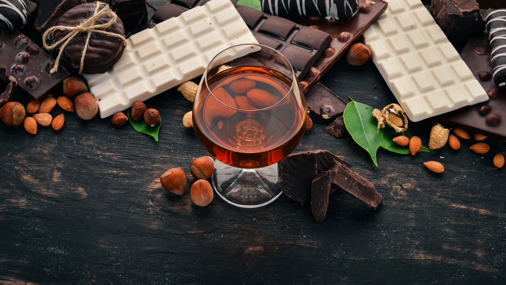 A glass of cognac, and a set of chocolate with cookies and sweets.